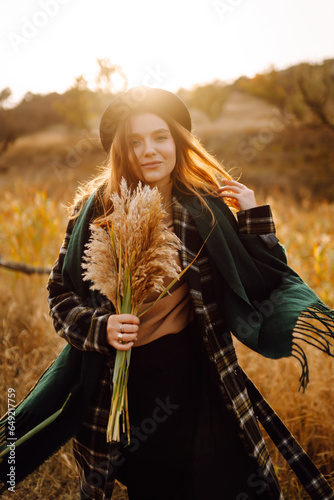 Portrait of a happy woman in stylish clothes having fun on a sunny autumn day in nature. Concept of fashion, style, relaxation or freedom.