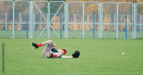 Baseball tournament at school, the boy pitcher did not catch the fastball, falling on the grass, dynamic sport game, missed the ball, slow motion.