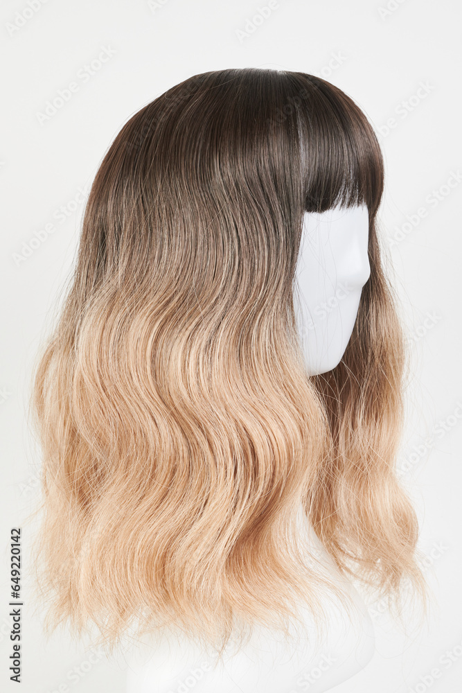 Naklejka premium Natural looking blonde fair wig on white mannequin head. Middle length hair cut on the plastic wig holder isolated on white background, side view.