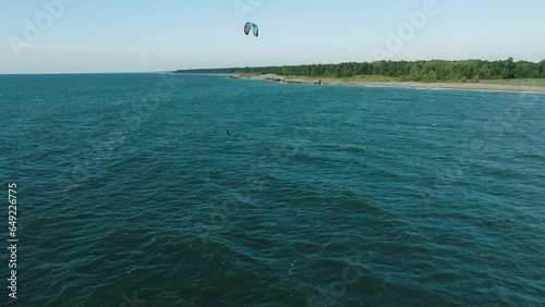 Establishing aerial view of a group of people engaged in kitesurfing, sunny summer day, high waves, extreme sport, Baltic Sea Karosta beach (Liepaja), birdseye drone dolly shot moving right