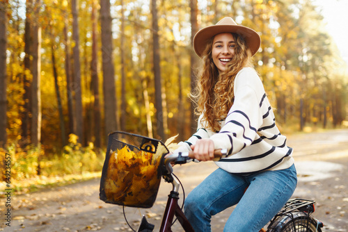 Tablou canvas Happy young woman riding a bike, having fun in the autumn park