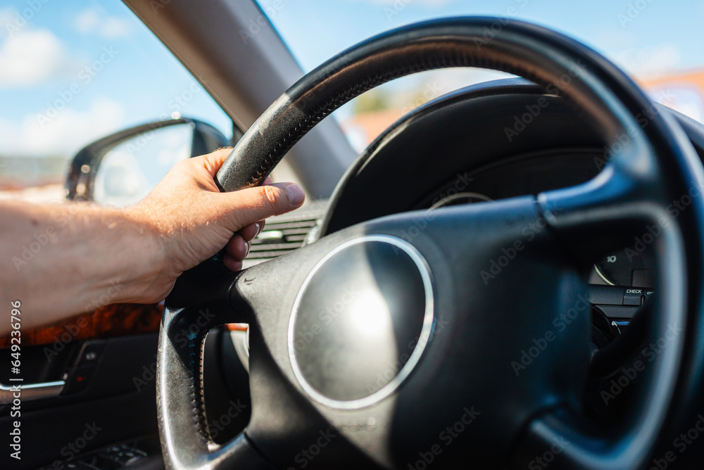 Man hand driving car on the traffic jam.Male driver hands holding steering wheel.Closeup.