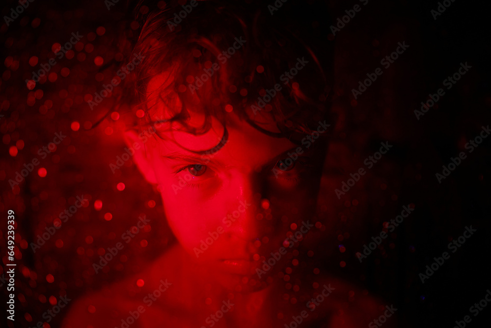 Offended boy with wet hair in red light
