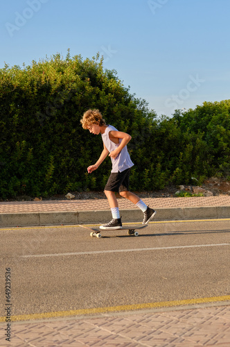 Boy riding skateboard along road © ADDICTIVE STOCK CORE