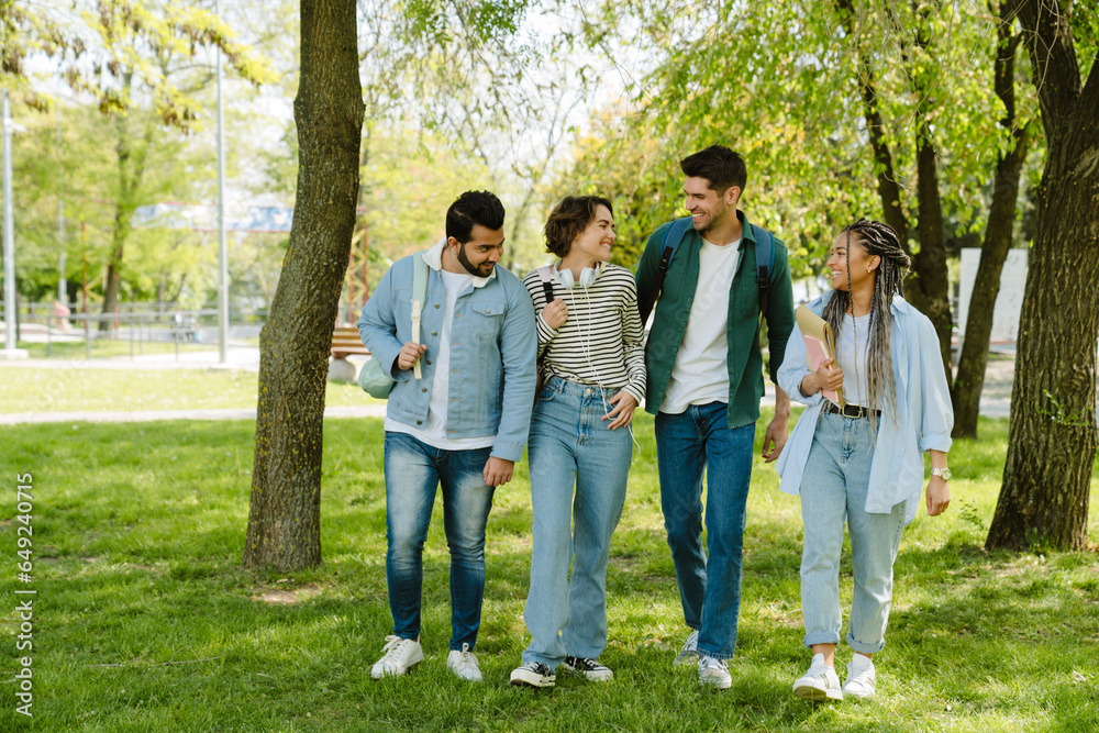 Four young students walking together in park Four young students walking together in park