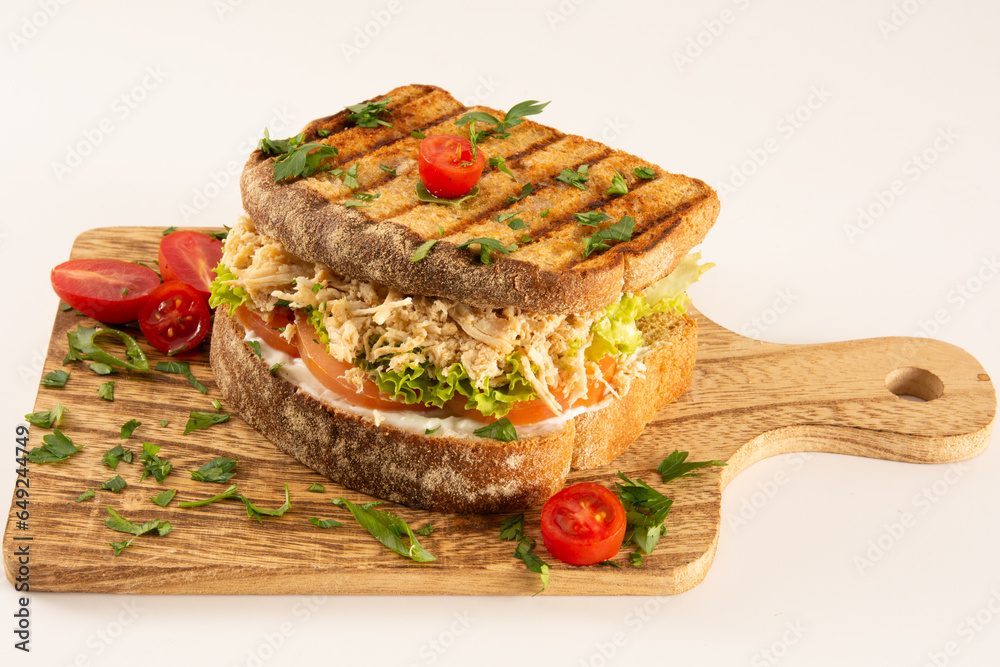 Chicken Breast Sandwich on Whole Grain Bread with Fresh Salad in a Wooden Table on a White Background in front view