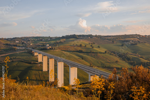 View of the E55 highway overpass. The overpass passes through the picturesque hills of the Abruzzo region in Italy. photo in yellow tones of sunset. photo