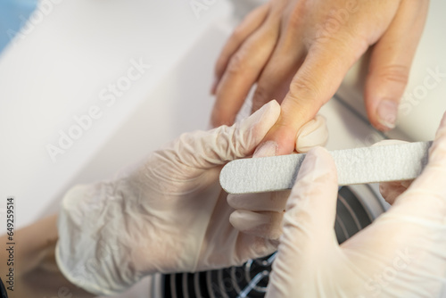 Nail care procedure in a beauty salon. Female hands and tools for manicure  process of performing manicure in beauty salon. Gloved hands of a skilled manicurist cutting cuticles. Concept spa body care