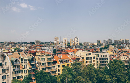 view of city with many beautiful colorful orange houses roofs and tall buildings 