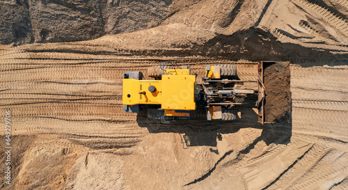 Yellow Industrial excavator working on sand quarry. Aerial top view open pit mine industry concept photo