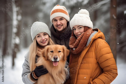 Close-up front view. Happy family walking their pet golden retriever in the winter forest outdoors. happy dog in front with a protruded tongue