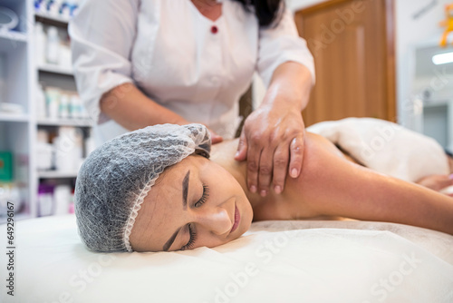 Gentle female hands of a woman masseur doing a back massage in a health spa beauty center.