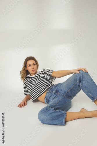 Fashion portrait of young woman in relaxed wide jeans and striped t shirt on the white background © triocean