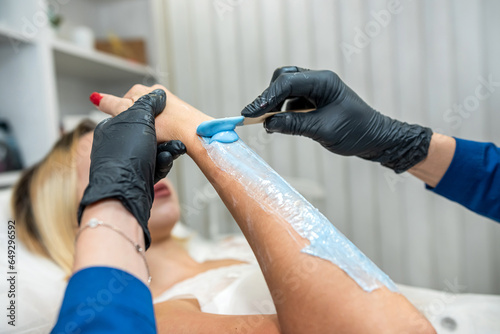 female doctor cosmetology putting cream hot wax gel on the hand