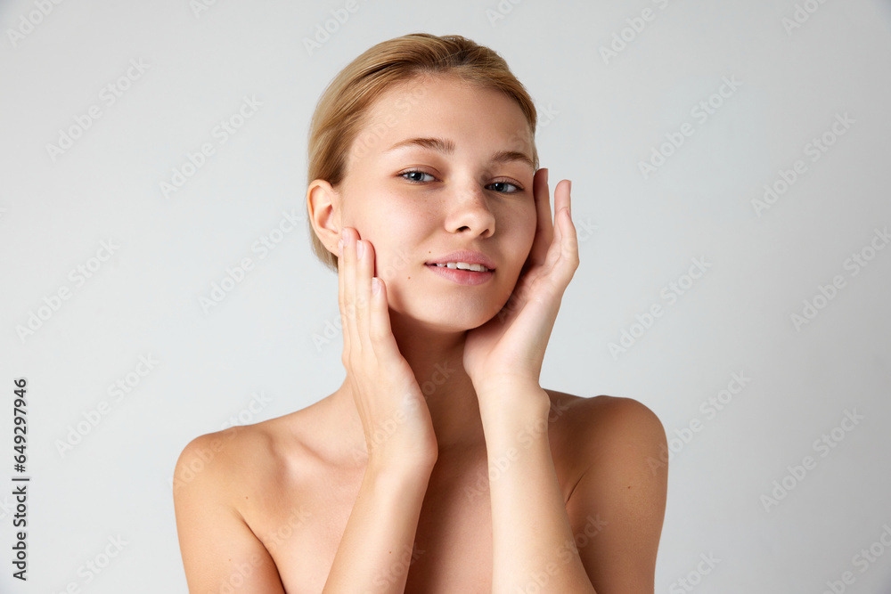 Portrait of attractive young girl with well-kept skin and perfect face shape isolated over grey studio background Portrait of attractive young girl with well-kept skin and perfect face shape isolated over grey studio background