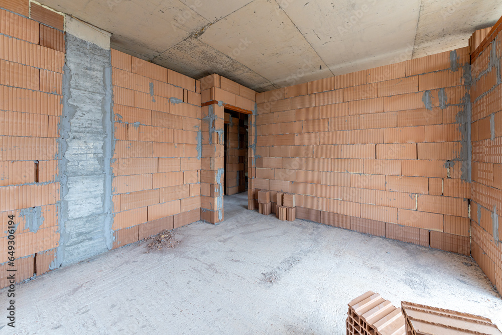 Obraz premium Unfinished room interior of building under construction. Brick red walls. New home.