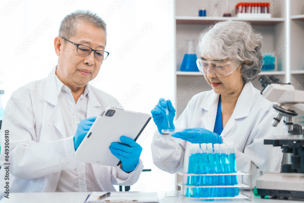 Senior scientists analyzing pharmaceuticals, asian people, senior man and woman, experienced experts in science, conducting pharmaceutical research in modern lab setting with powerful microscope.