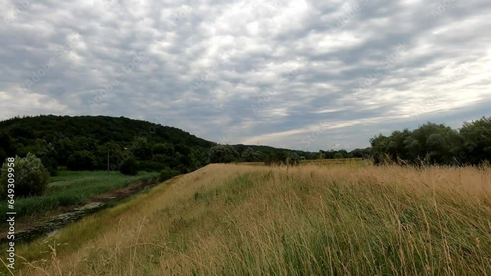 Altocumulus clouds in time-lapse mode and green summer meadow in the foreground, fluffy clouds and the blue sky Altocumulus clouds in time-lapse mode and green summer meadow in the foreground, fluffy clouds and the blue sky