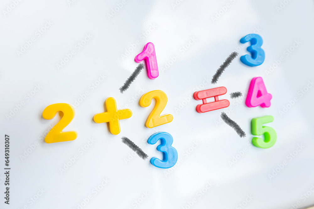 White board with magnetic numbers, primary school math. Solving examples White board with magnetic numbers, primary school math. Solving examples
