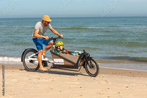 Papa und Kind haben Spaß mit dem Lastenrad am Strand,Skagen,Dänemark photo