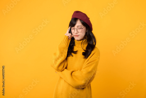 Lifestyle, people emotions and casual concept. Thoughtful stylish young asian woman wearing yellow shirt, dreaming or imaging perfect plan, have interesting idea, thinking against yellow background. © Jirawatfoto