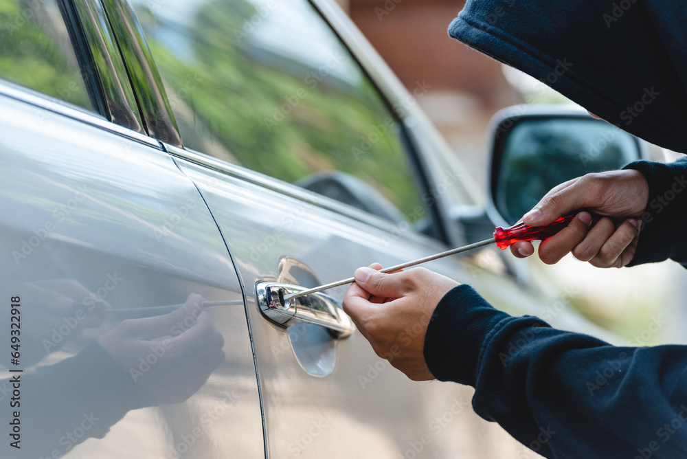 Car thief with mask steal robber trying to open car door by screwdriver