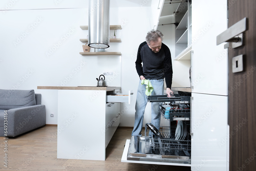 Older man cleaning kitchen space in apartment Older man cleaning kitchen space in apartment
