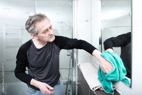 Older man cleaning bathroom space in apartment photo