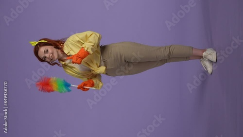 Woman in casual clothing and rubber gloves holding colorful pipiduster, pointing at it and showing thumbs up, smiling at the camera. Vertical video. photo