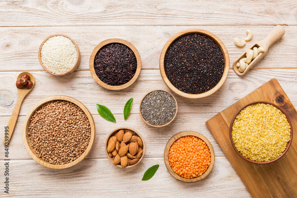 Various superfoods in smal bowl on colored background. Superfood as rice, chia, quinoa, lentils, nuts, sesame seeds, almonds. top view