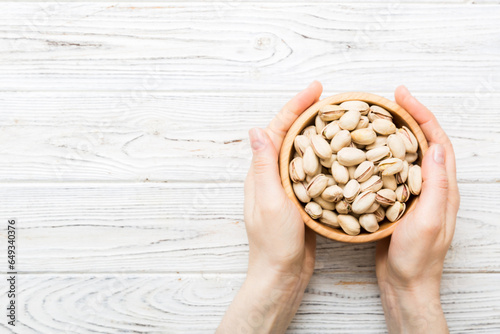 Woman hands holding a wooden bowl with pistachios nuts. Healthy food and snack. Vegetarian snacks of different nuts