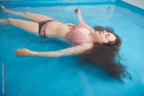 Wellness - young woman floating in Spa or swimming pool, she is very relaxed.