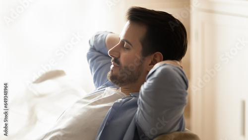 Close up profile peaceful calm man leaning back on cozy couch, meditating or daydreaming in living room, enjoying lazy weekend, relaxing with closed eyes, stretching on sofa at home