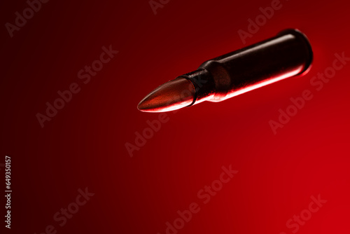 Rifle bullet long cartridge on red background. Army or hunting weapon shot object  violence and danger symbol.