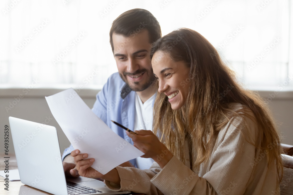 Happy young woman reading letter, loving couple excited by good news, taxes refund or mortgage loan approval notification, family planning budget, using laptop and online banking service Happy young woman reading letter, loving couple excited by good news, taxes refund or mortgage loan approval notification, family planning budget, using laptop and online banking service