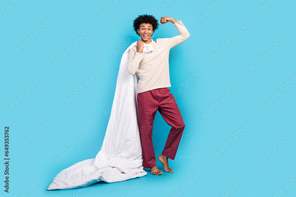 Full size photo of cute young guy hold blanket raise fist flexing power