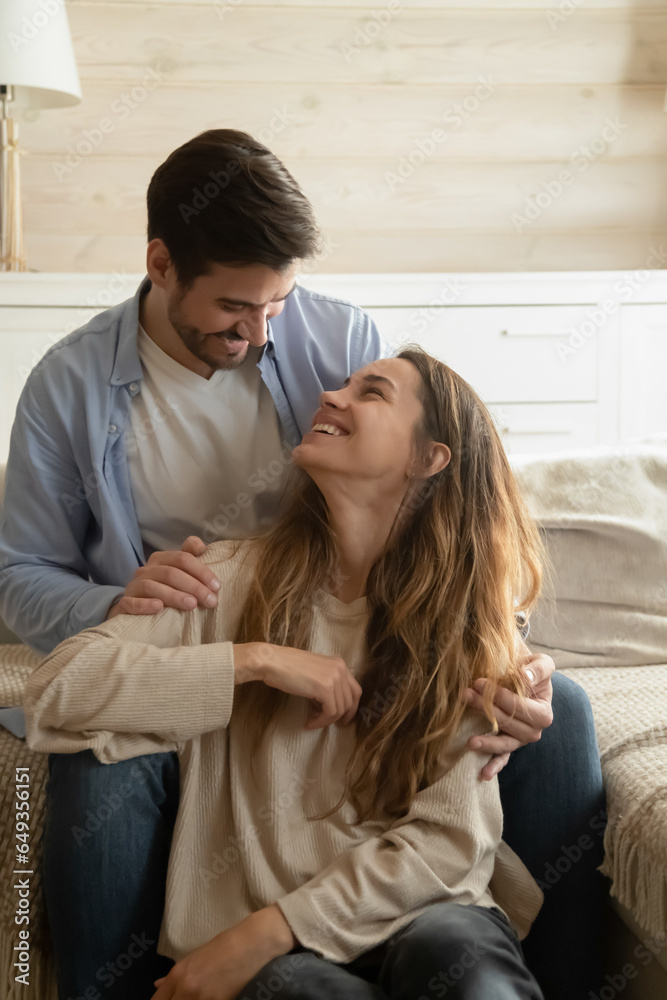 © fizkes - Happy couple enjoying tender moment together, looking at each other, smiling young woman sitting on floor, loving husband touching wife shoulders, family having fun in living room, vertical photo © fizkes - Happy couple enjoying tender moment together, looking at each other, smiling young woman sitting on floor, loving husband touching wife shoulders, family having fun in living room, vertical photo