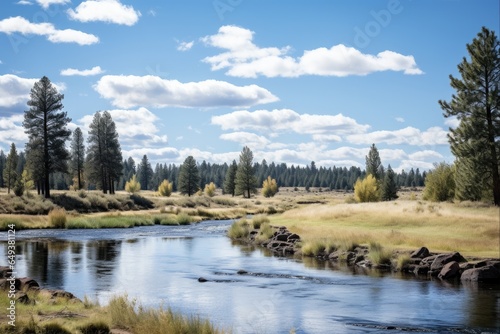 Adventure in Sunriver Oregon: Daytime View of Deschutes River with Evergreens, Bushes and Brook in the Foreground under Blue Skies and Clouds