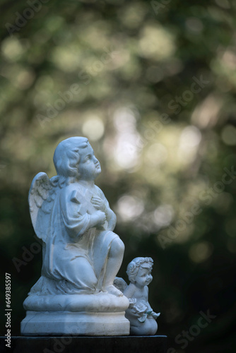 Zwei kleine Engelsfiguren vor grünem Naturhintergrund auf Friedhof, keine Namen © Winfried