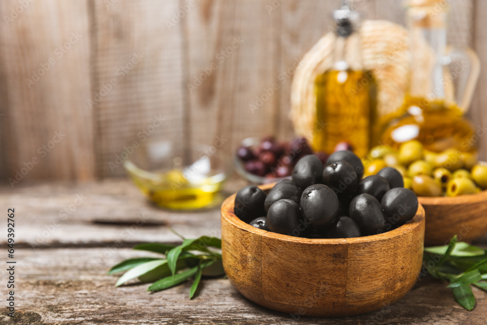 Set of black and green olives on a white wooden background. Various types of olives in wooden bowls and fresh olive leaves. Copy space. Place for text. flat lei. Delicatessen. Set of black and green olives on a white wooden background. Various types of olives in wooden bowls and fresh olive leaves. Copy space. Place for text. flat lei. Delicatessen.