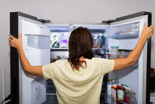 woman with her back looking inside the refrigerator out of craving or famine. lack of food
