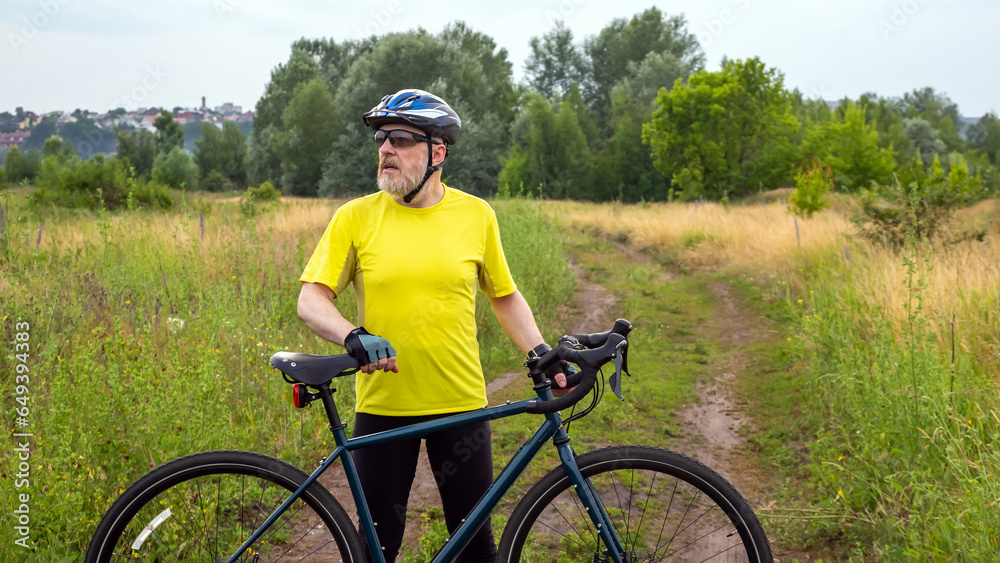 bearded man cyclist in yellow clothes is resting on a bicycle on the road in nature. sports, hobbies and entertainment for health bearded man cyclist in yellow clothes is resting on a bicycle on the road in nature. sports, hobbies and entertainment for health