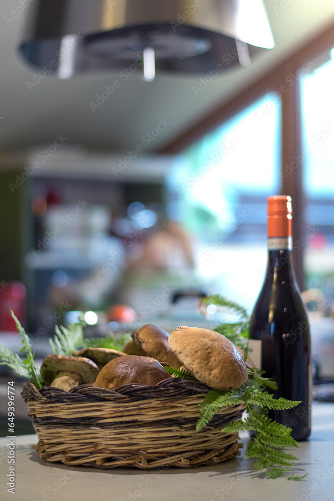 Basket of porcini mushrooms on kitchen table next to a bottle of Italian wine