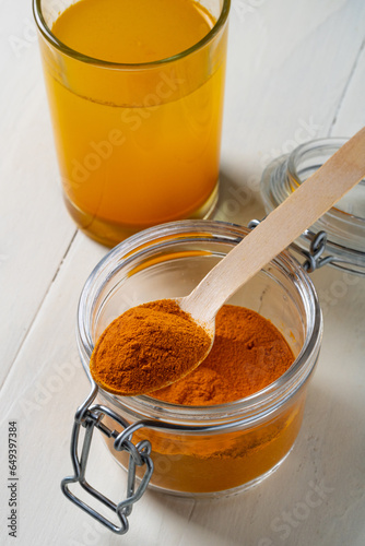 Turmeric in a glass jar and a glass of water with turmeric on the table