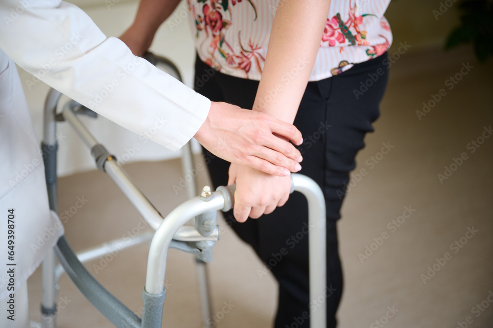 Fototapeta premium Doctor holding a patient's hand, helping to move. Walkers for adults. Rehabilitation after stroke. Physiotherapy in the hospital. Close up view of the hands.