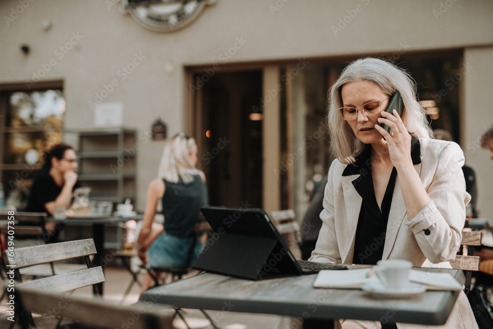 Portrait of beautiful female manager in middle age with gray hair making a phone call outdoors. Portrait of beautiful female manager in middle age with gray hair making a phone call outdoors.