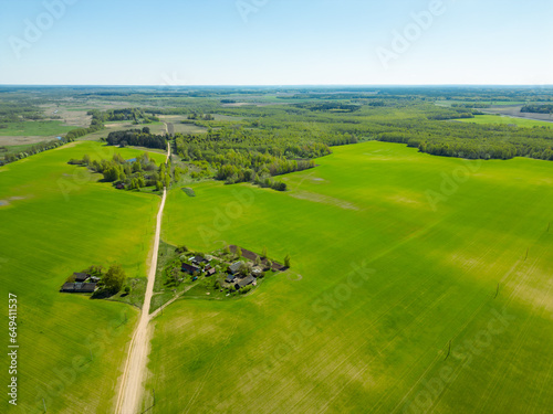 Aerial view of a beautiful agricultural field along the forest during sunset. Top view of fields riddled with rural dirt roads. Natural landscape.