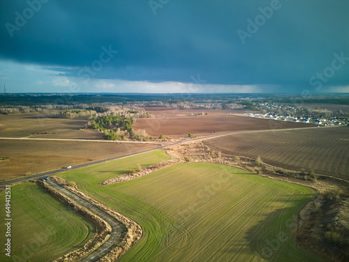 A dark thundercloud is moving over a rural field. A cloud with a clearly visible rain line. Aerial view over an agricultural field during rain. The drone is flying in a field in the rain.