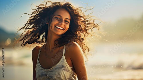 dark skinned young laughing woman in front of a blurred beach © Claudia Nass