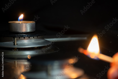 A lit match and a candle on a gas burner